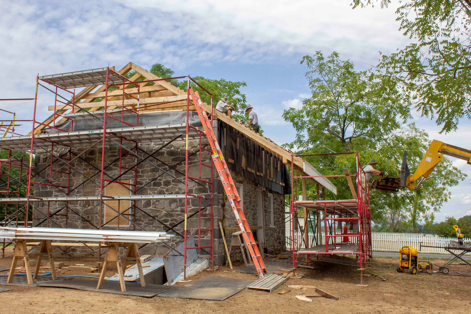A worker installs shingles on a roof.