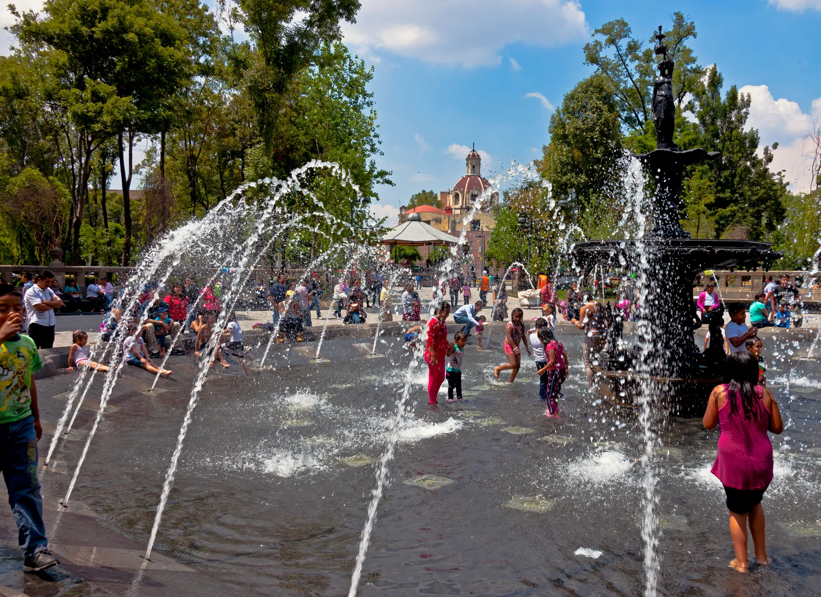 People cooling off at a public fountain on a hot day.