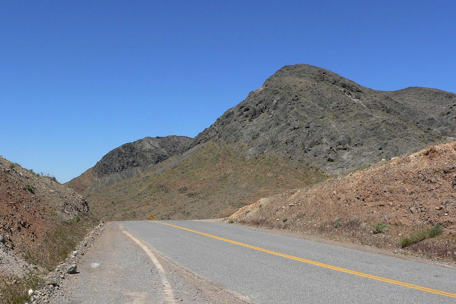 An empty desert highway stretching toward distant mountains.