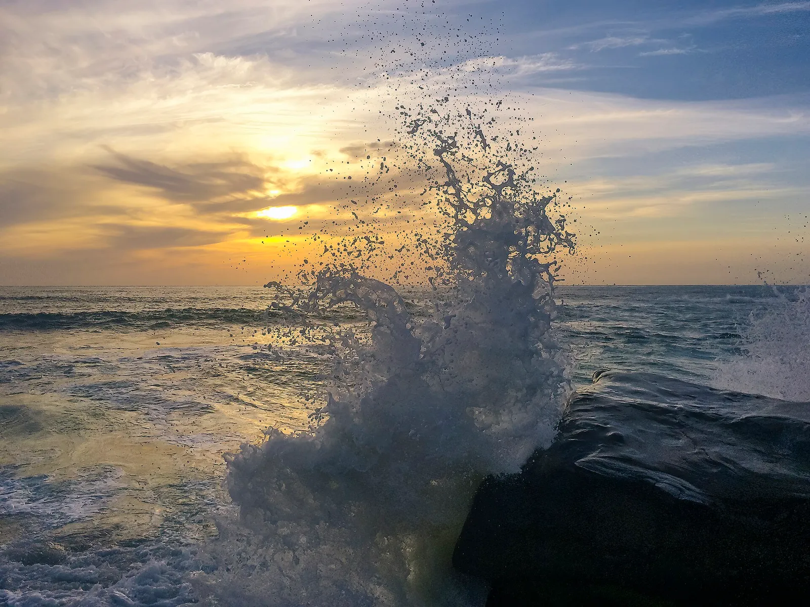 Large waves crashing on rocks along the California coast.