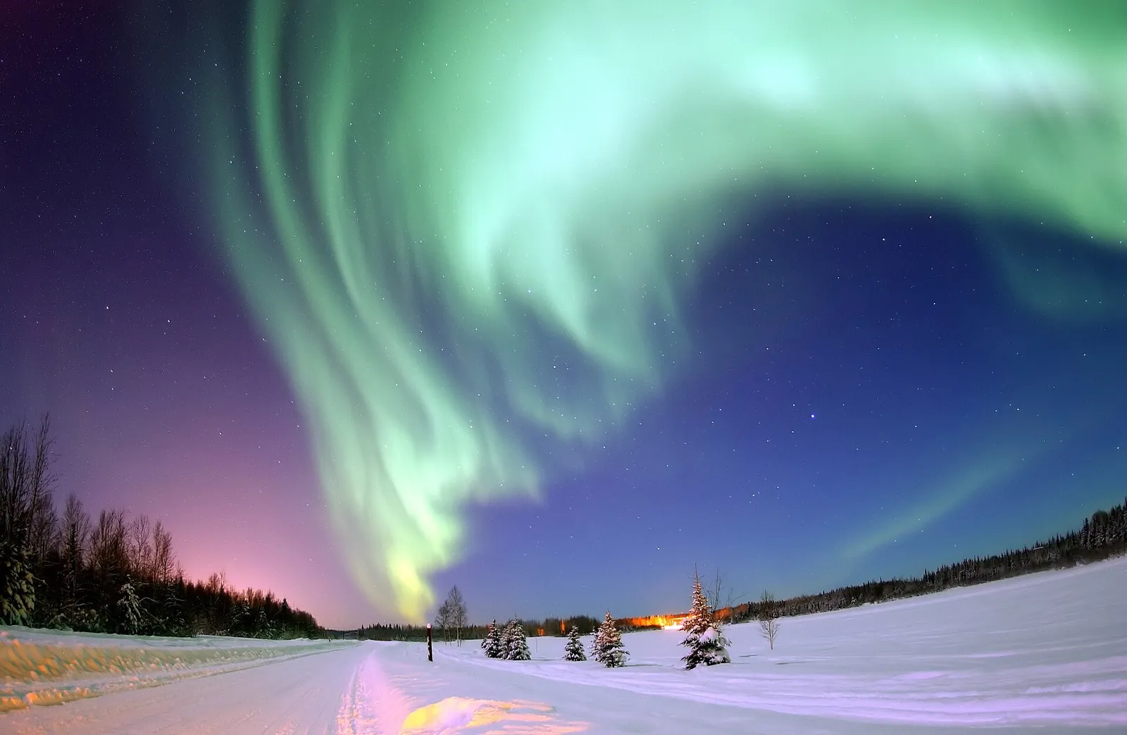 The aurora borealis glows green over a landscape in Alaska.