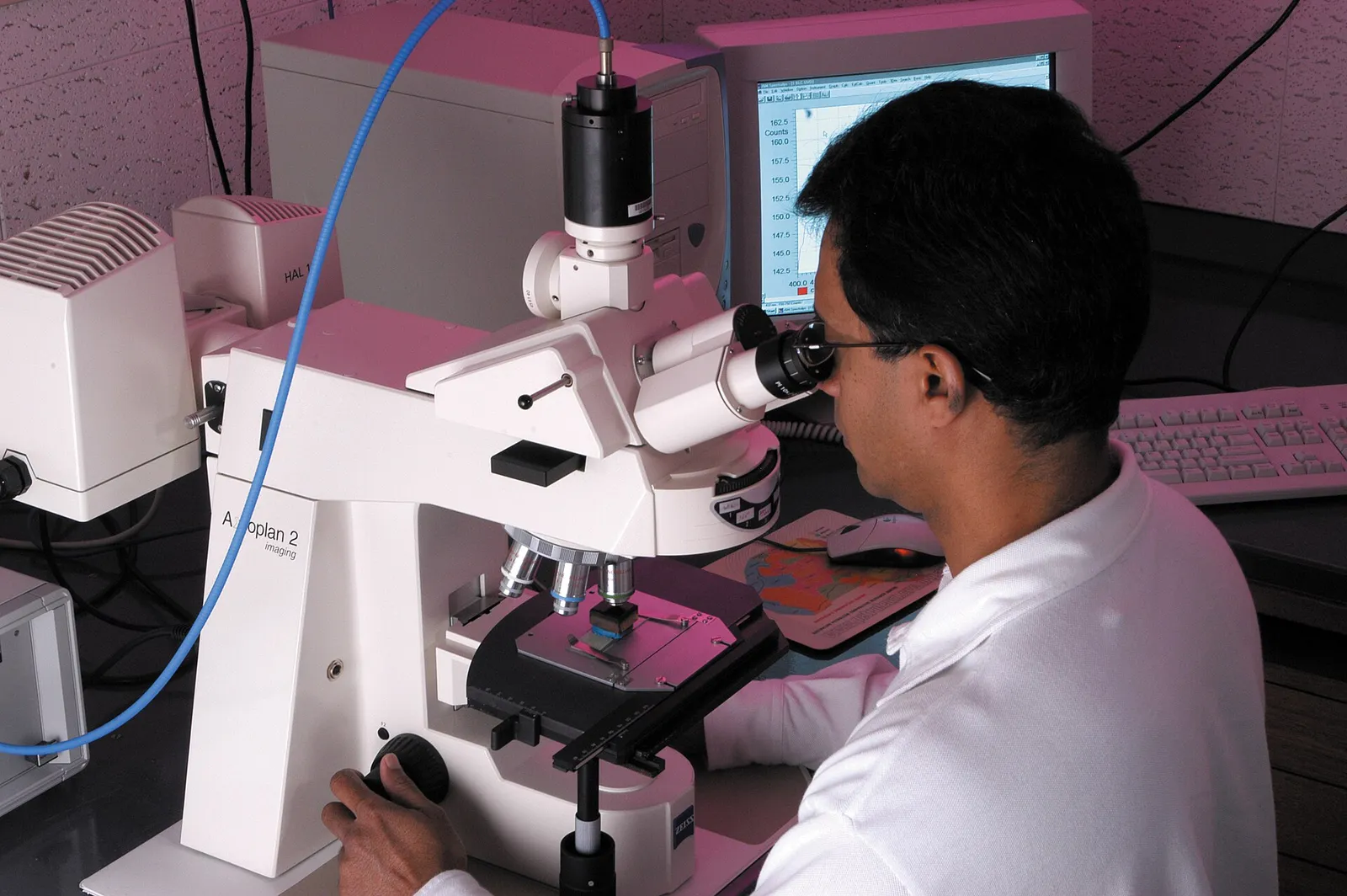 A scientist examines a sample under a microscope in a laboratory