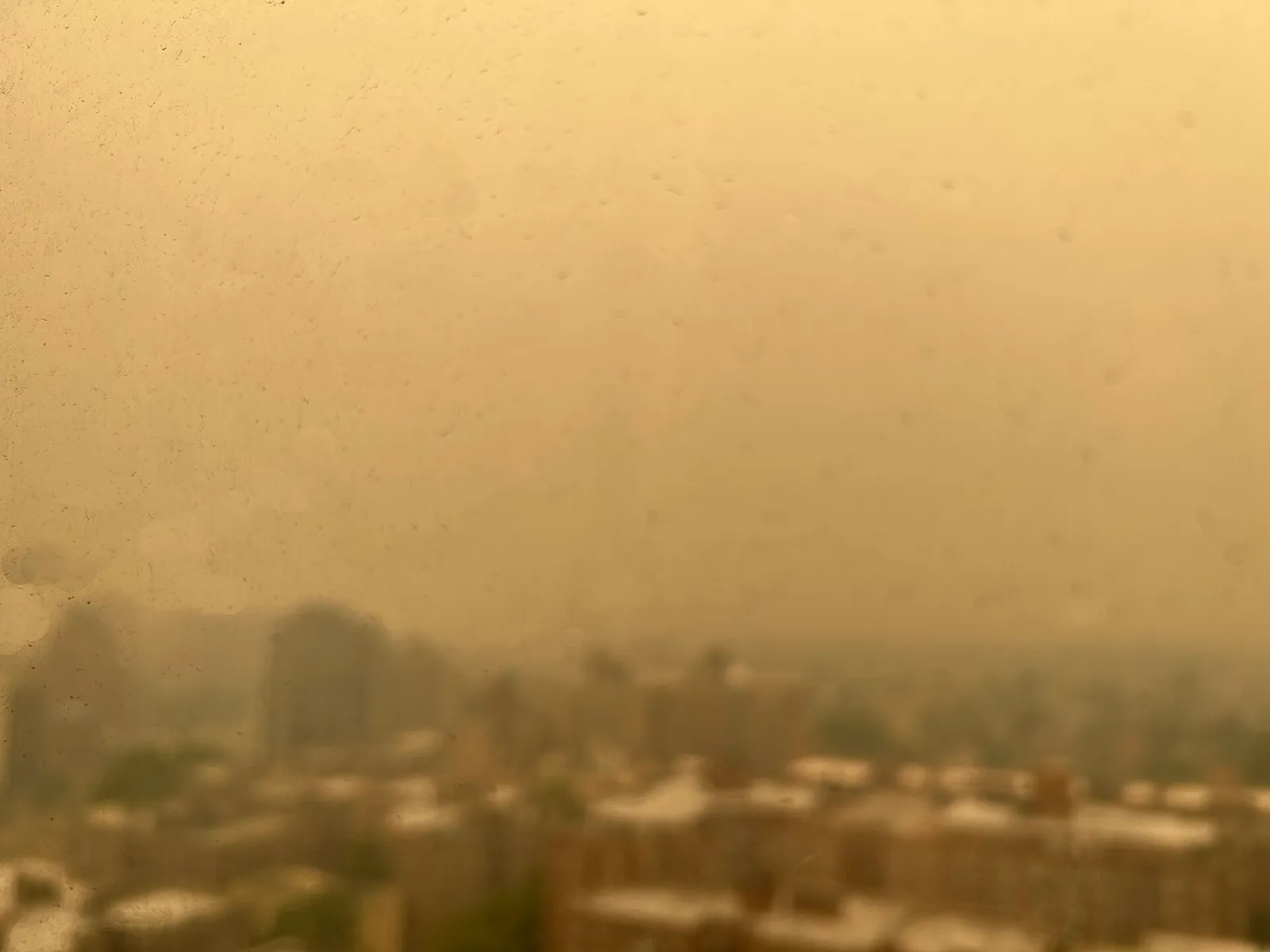Orange wildfire haze obscures a city skyline