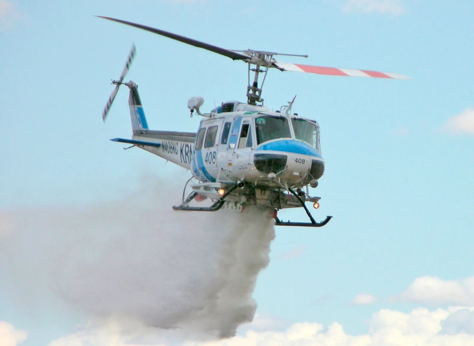 A firefighting helicopter releasing a water drop in flight