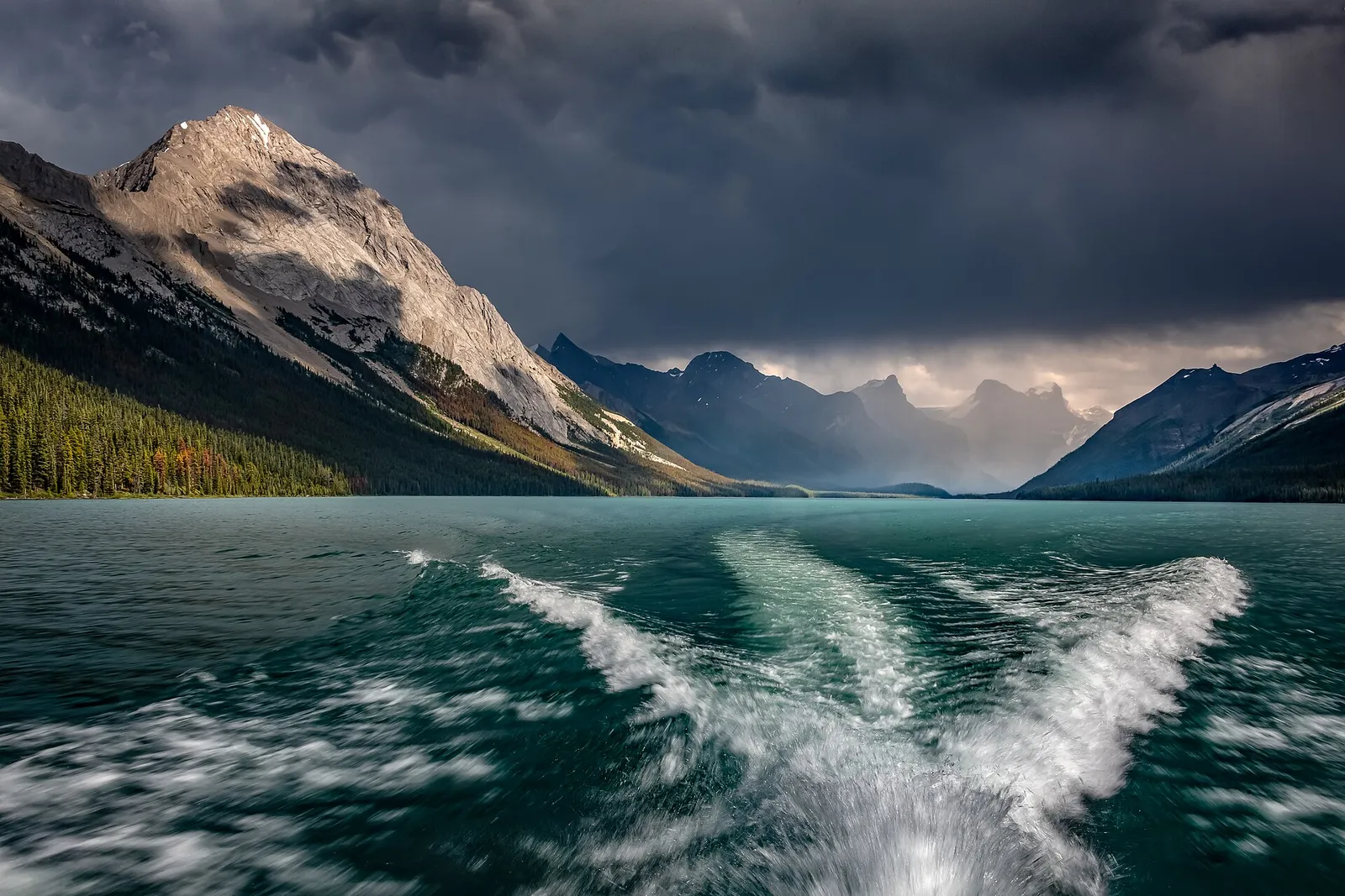 A boat on a lake beneath gathering storm clouds.