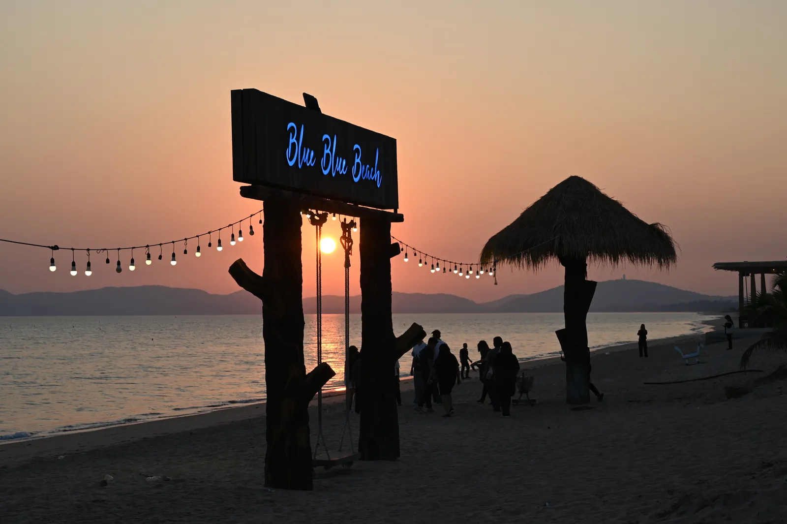 A tropical beach at golden hour with palm-thatched huts and string lights (illustrative).
